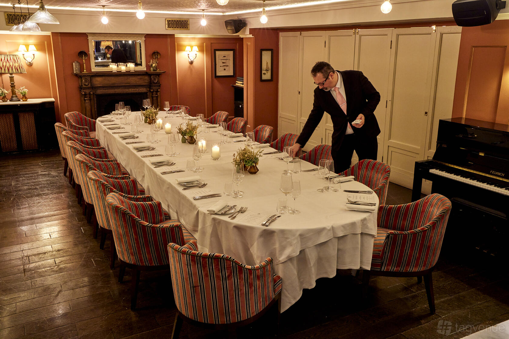 A private dining room with a long banquet table, striped upholstered chairs, and candlelit floral centerpieces at Bentley's Oyster Bar & Grill.