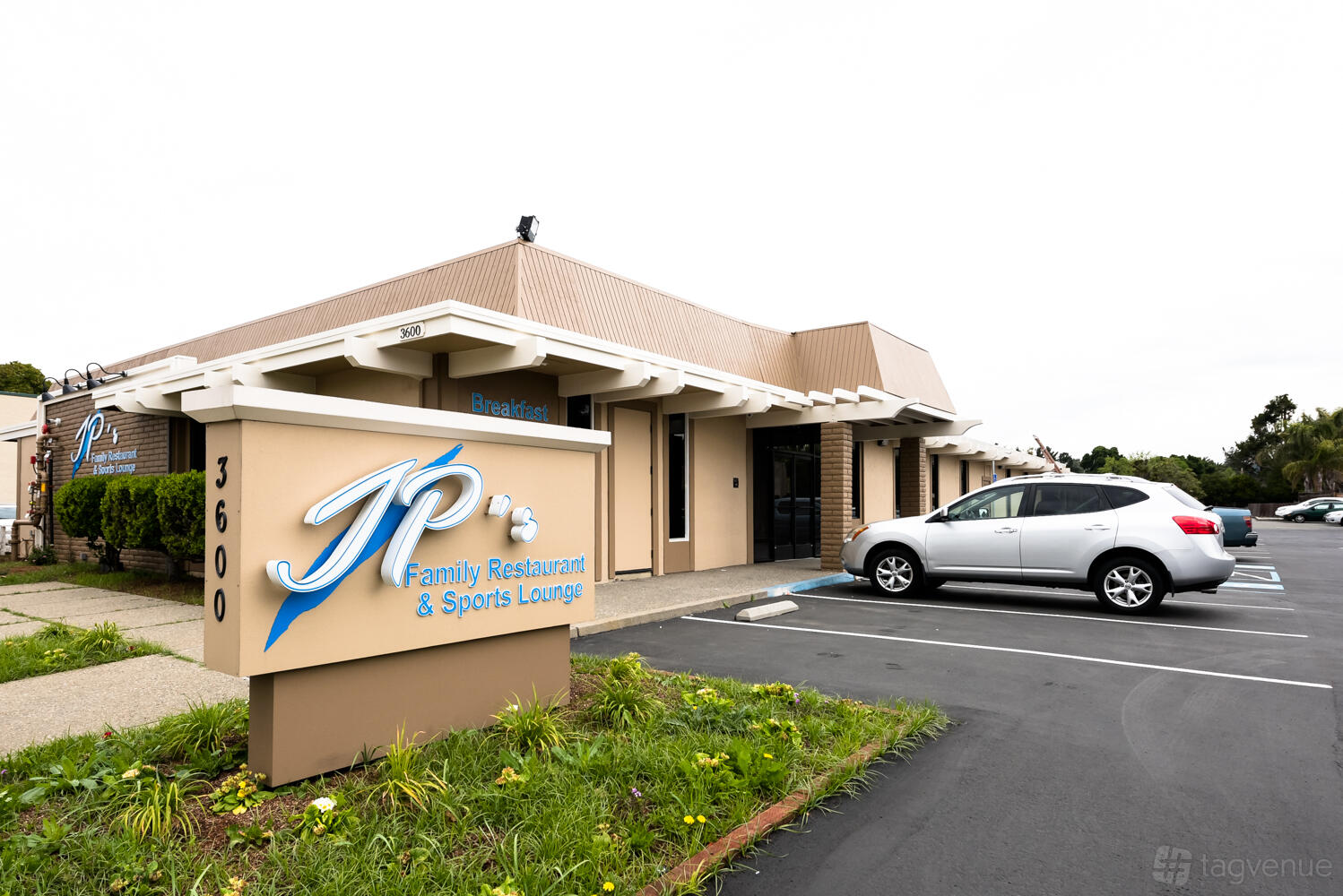 A restaurant with a beige exterior, large front windows, and a sign reading JP's Family Restaurant & Sports Lounge.