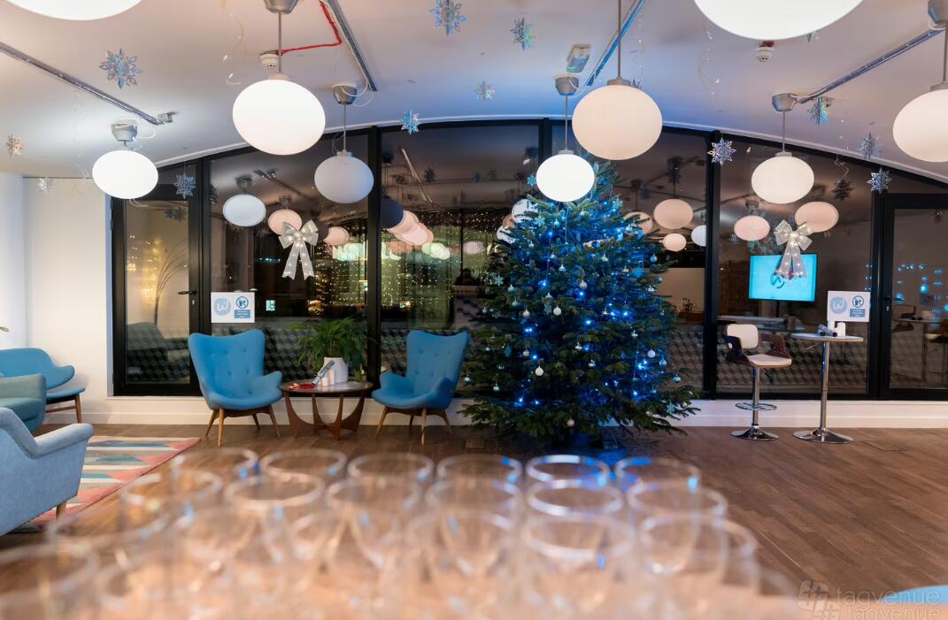 A function room with a decorated Christmas tree, round pendant lights, and blue armchairs at Wallacespace Clerkenwell Green.
