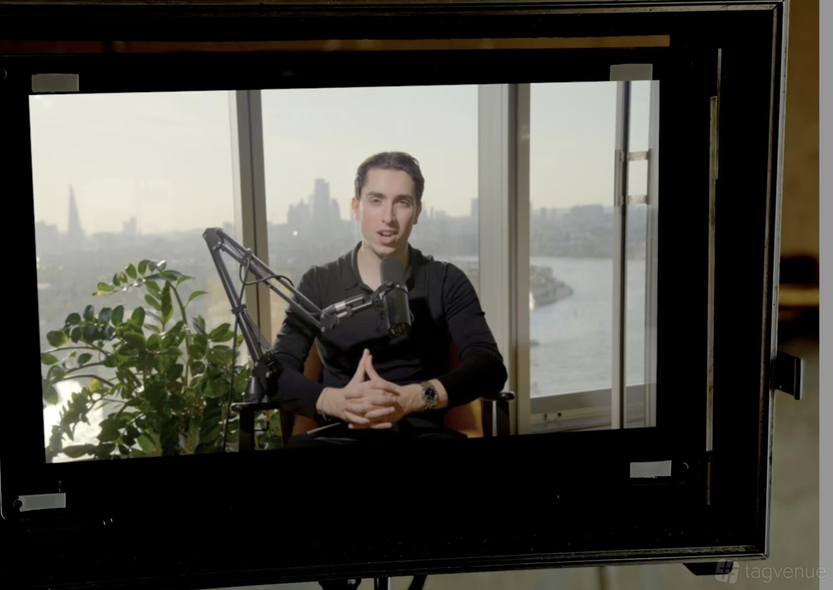 A podcast studio with a large window, river views, recording microphone, and leafy plant at Podcast Recording Studio.