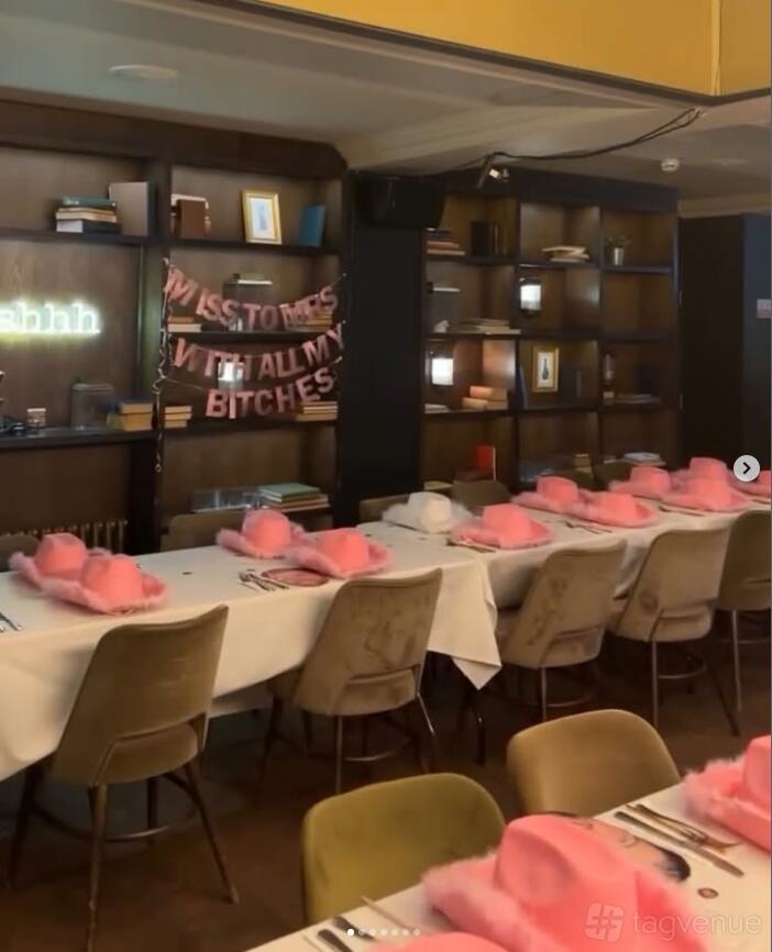 A function room with long banquet tables, pink hats as décor, and bookshelf walls at The Lost and Found Greek Street.