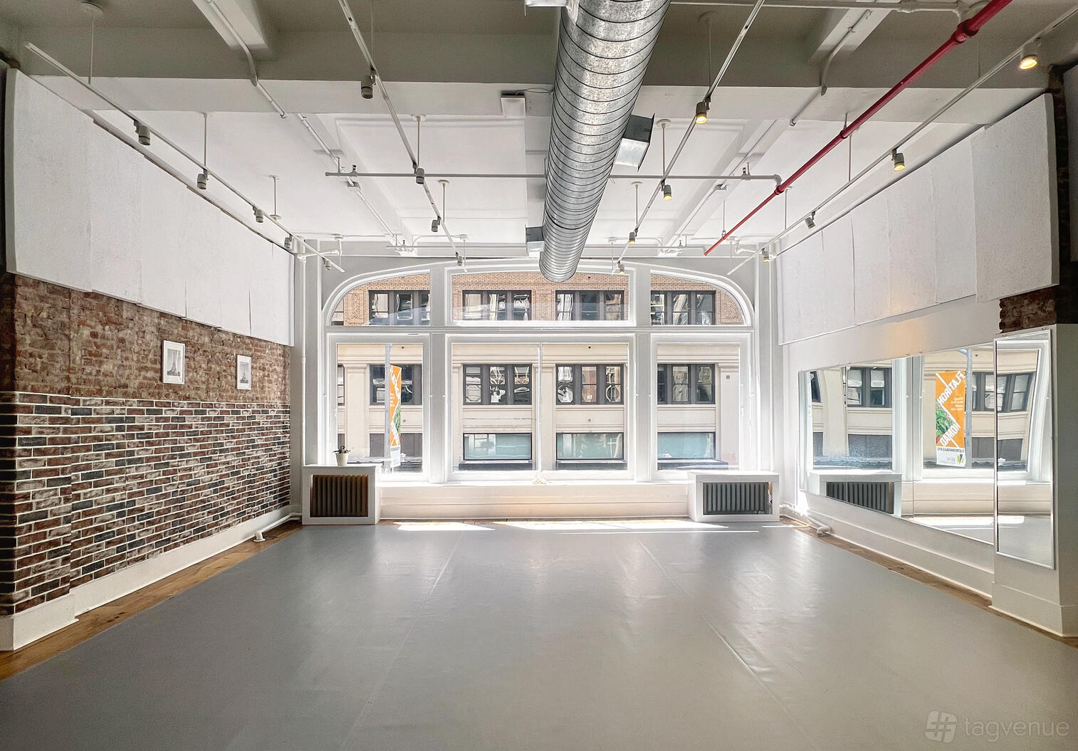 A dance studio with floor-to-ceiling mirrors, exposed brick walls, and large windows at Center for Performing Arts and Dance.