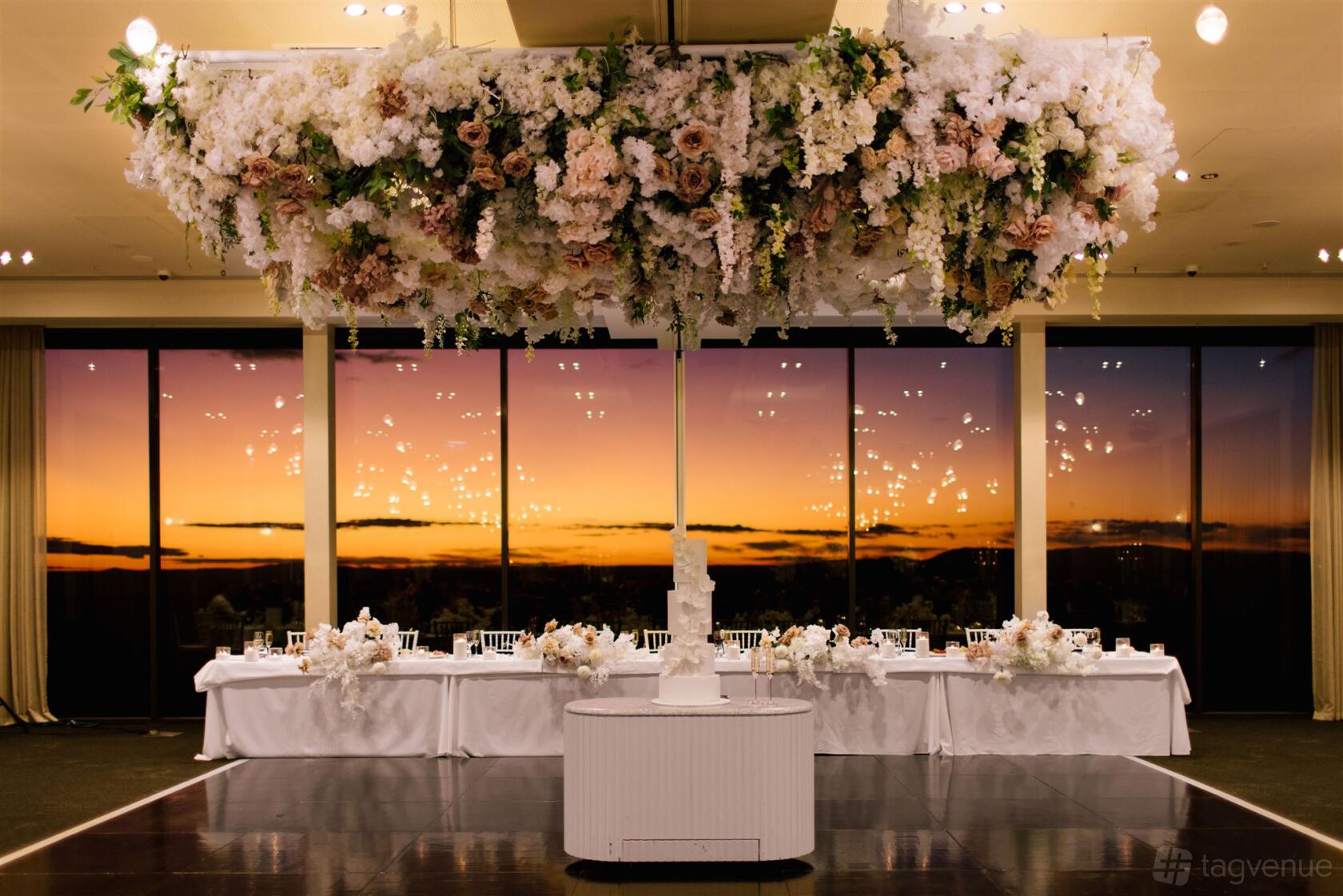 An event space with floor-to-ceiling windows, sunset views, and a ceiling floral installation at Marnong Estate.