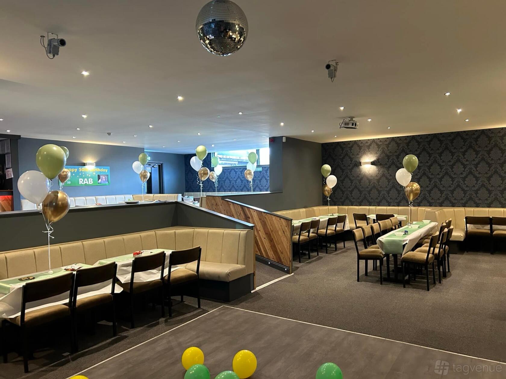 A function room with long banquet tables, beige upholstered seating, and decorative balloons at Thorniewood Park.