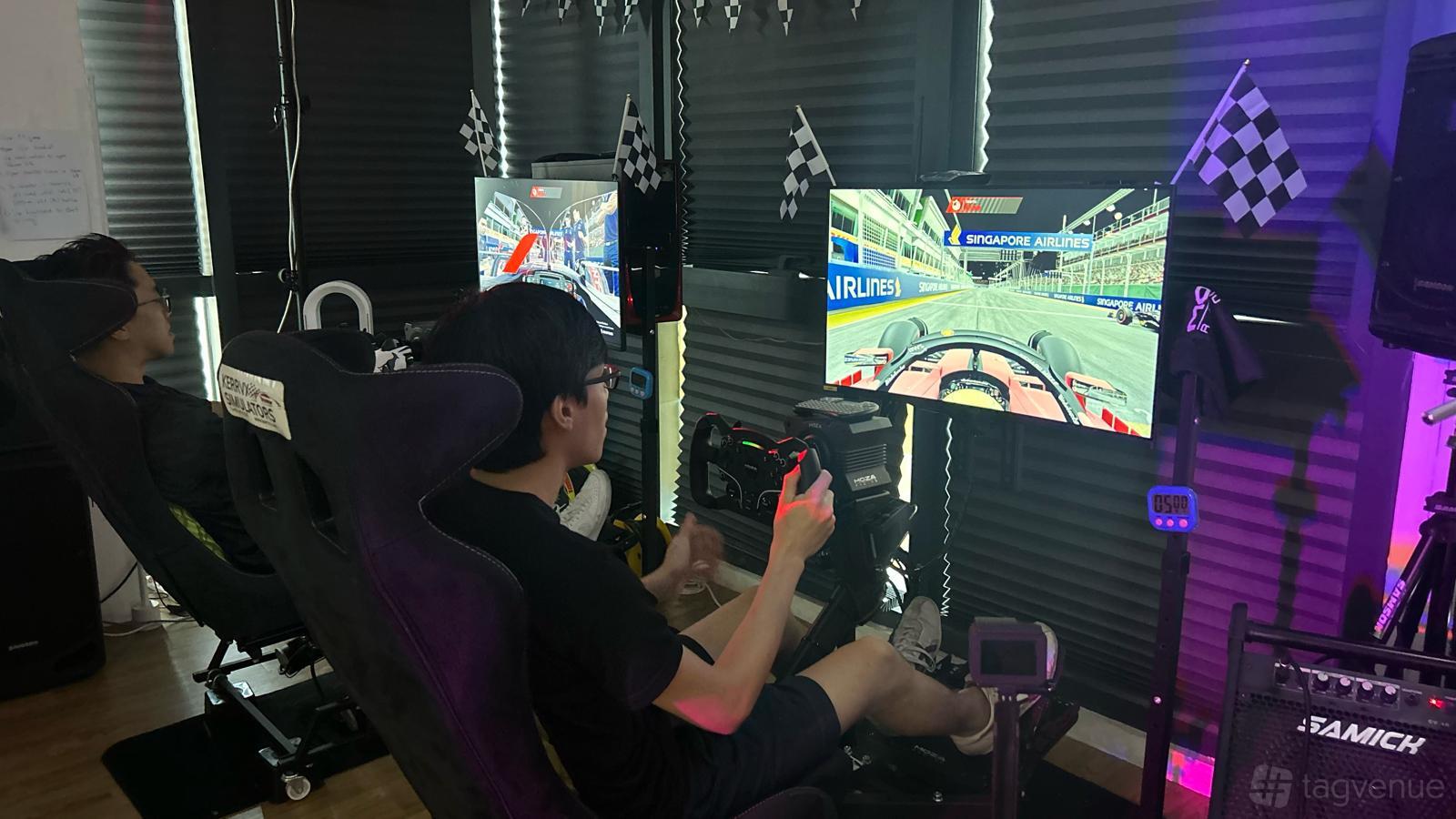 An event venue with racing simulator seats, steering wheels, and gaming monitors at LtzMeet F1 Simulator Racing.