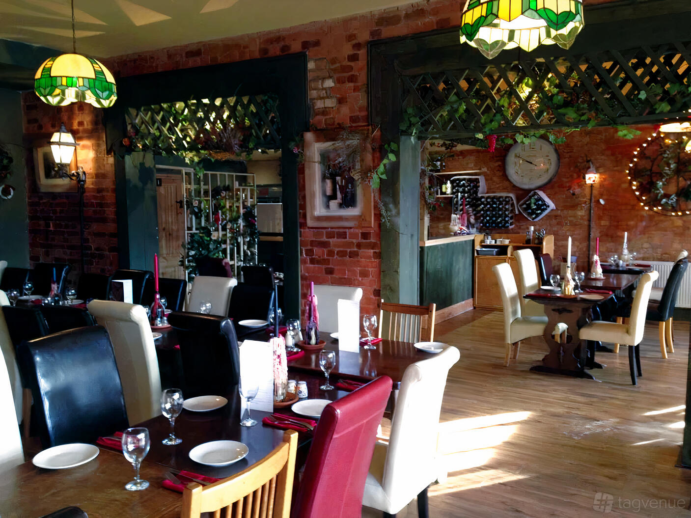 A restaurant with exposed brick walls, mismatched chairs, and decorative wall clocks at The Clock Bistro.