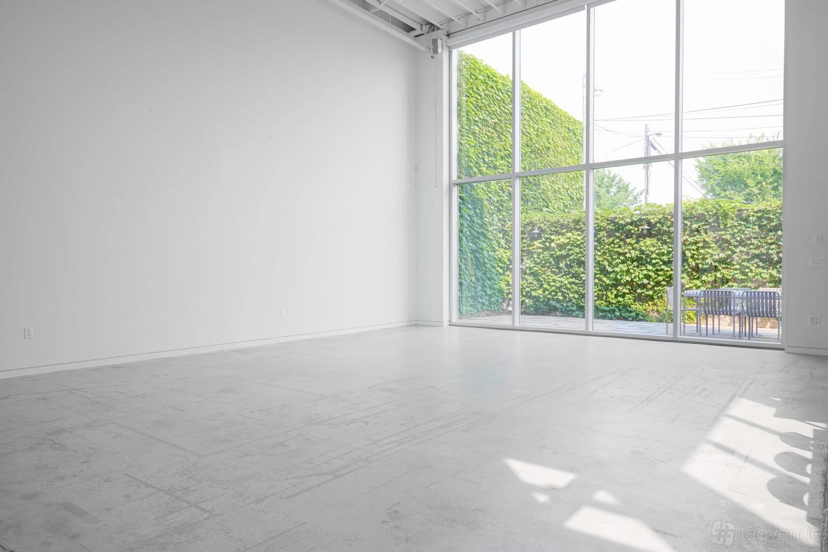 An event space with tall ceilings, white walls, and floor-to-ceiling windows overlooking a patio at Album Studios: Geary.