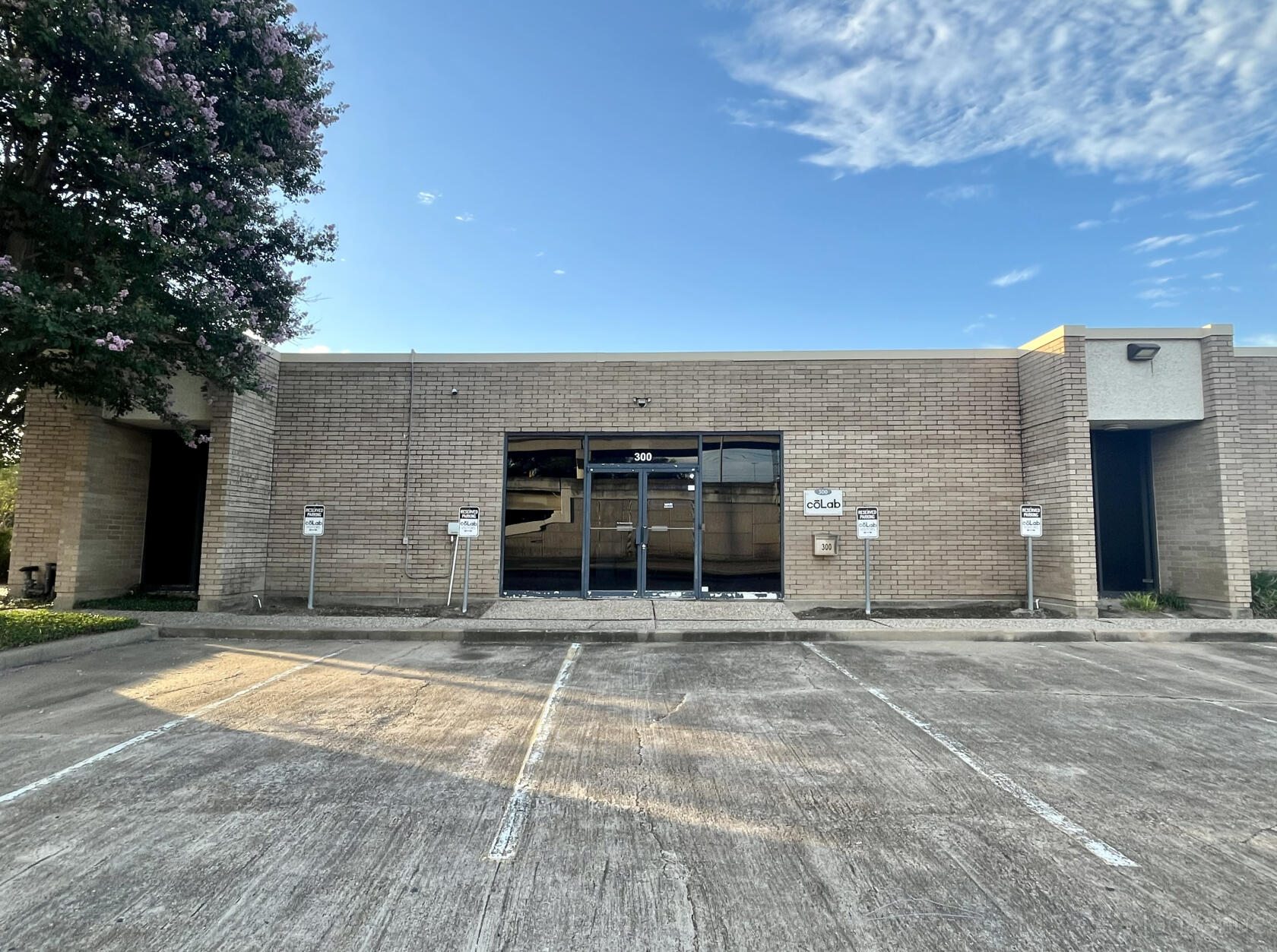 A film and photo studio with a brick exterior, glass double doors, and reserved parking at CoLab Production House.