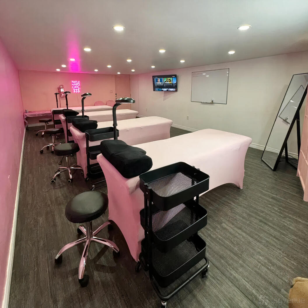 An event space in a loft with treatment beds, task lighting, and pink accents at Lashed Toronto Academy.