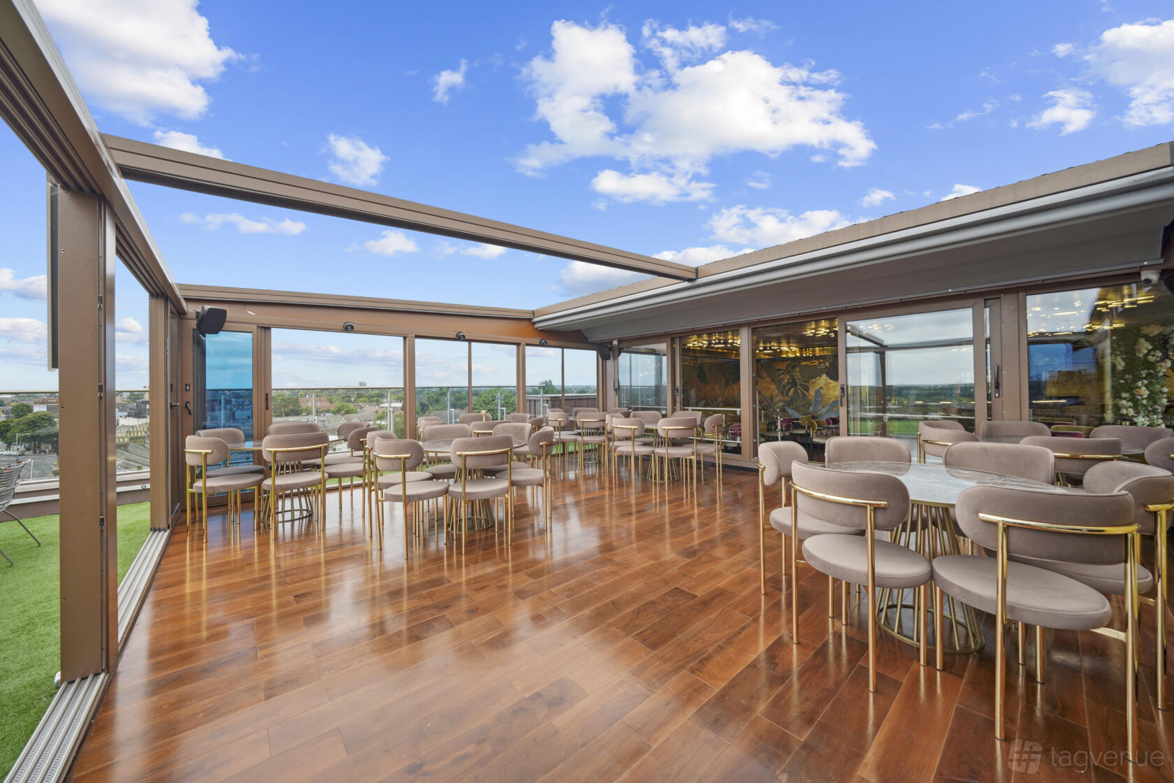 A restaurant with floor-to-ceiling windows, open roof panels, and wood floors at Godino Sky Bar & Restaurant.
