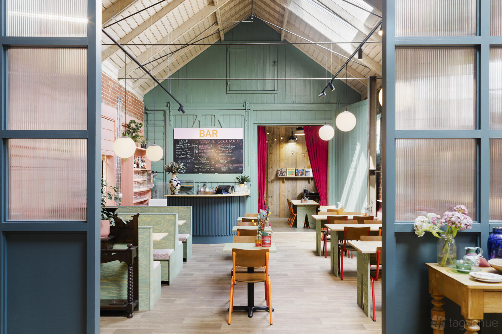 An event venue with high vaulted ceilings, skylights, a central bar, and colorful dining tables at New Street Market.