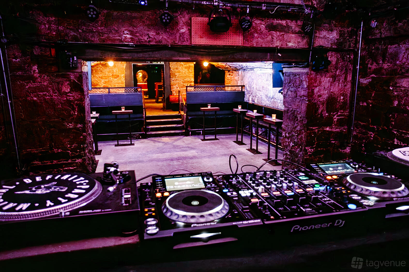 A nightclub with exposed stone walls, a DJ booth, and booth seating at The Cabaret Voltaire.