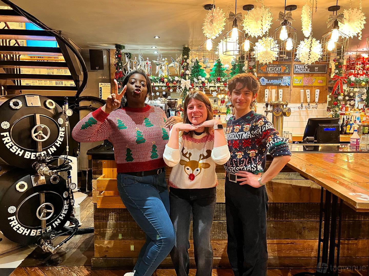 A restaurant with wooden bar counters, Christmas decorations, beer taps, and large brewing tanks at Tank and Paddle Bishopsgate.