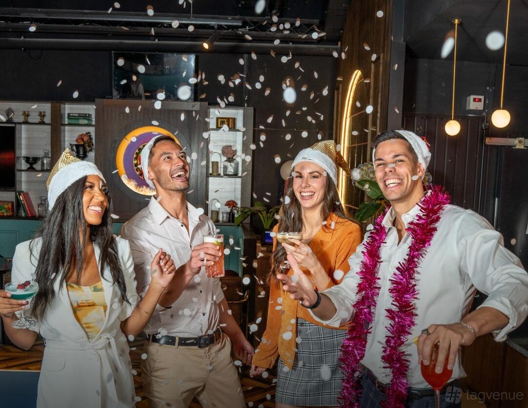 A function room with festive hats, confetti, and friends holding drinks at Ballers Clubhouse CBD.