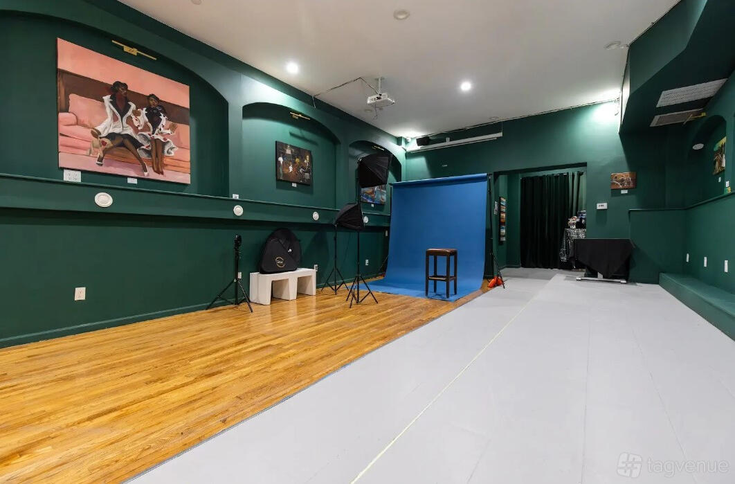 A cafe with green walls, art paintings, hardwood flooring, and a photography setup with a blue backdrop at Cafe Melo.
