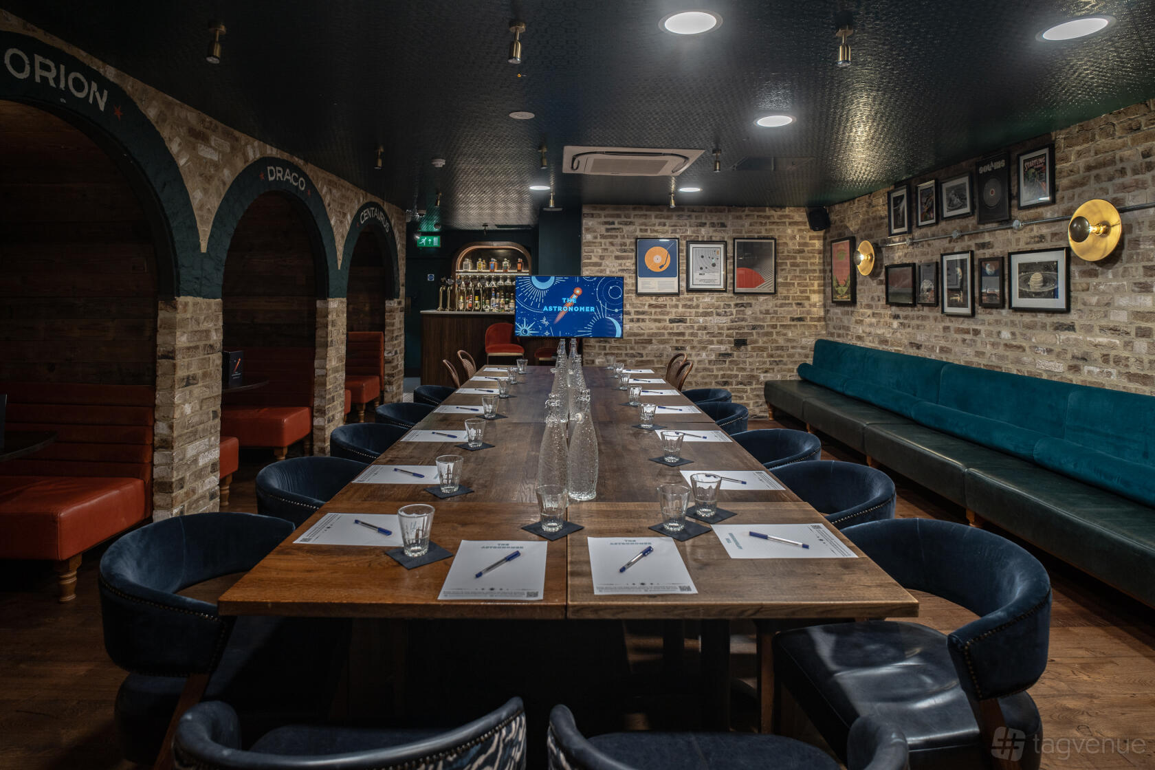 A function room in a pub with exposed brick walls, a long wooden table set for a meeting, and music-themed wall decor at The Astronomer.
