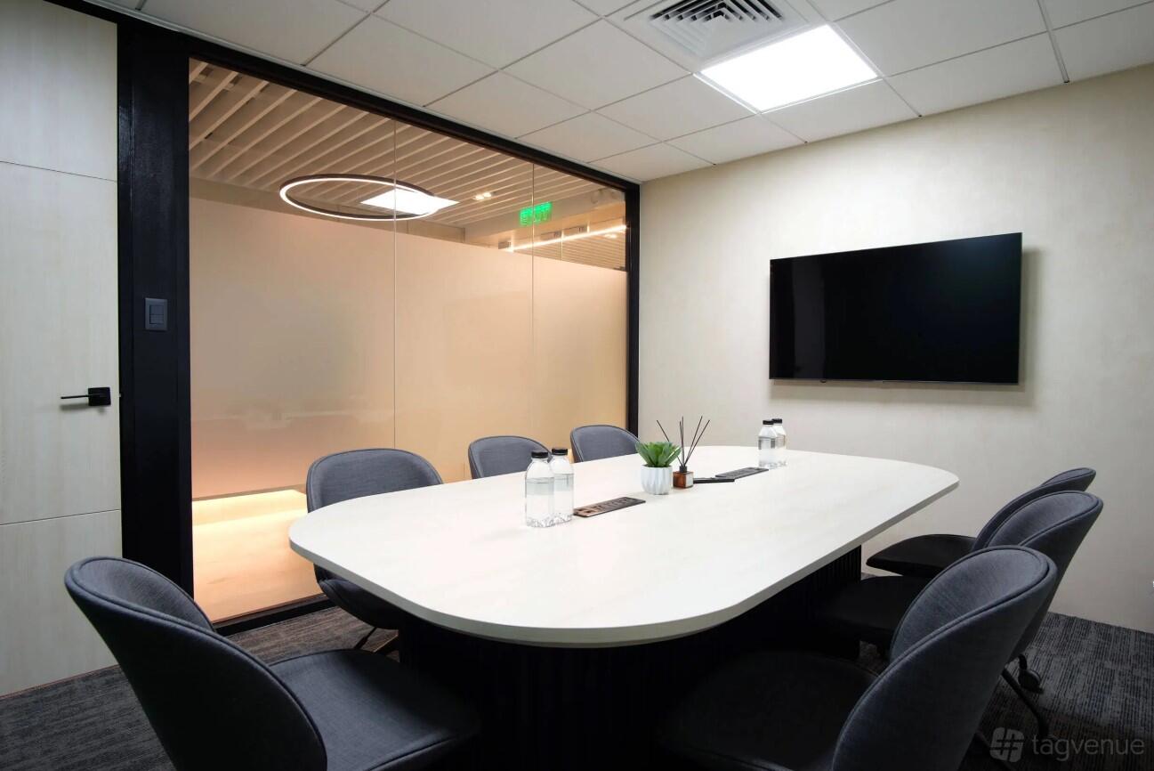 A meeting room with a rectangular table, six chairs, wall-mounted screen, and frosted glass wall at Regus - Belfast, Cathedral Quarter.