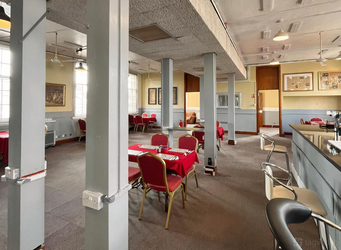 A cafe with red-covered tables, cushioned chairs, and large windows at The Palace Cafe.