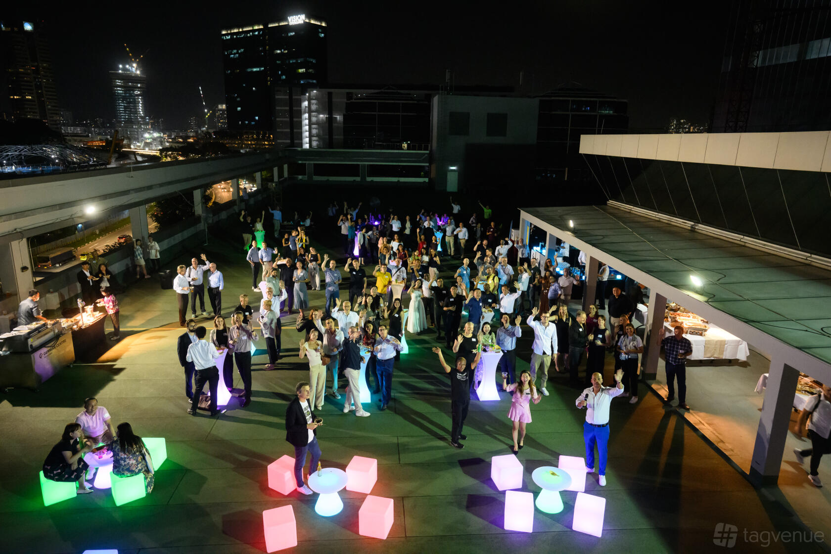 A rooftop event space with colorful illuminated tables and city skyline views at German Centre Singapore.