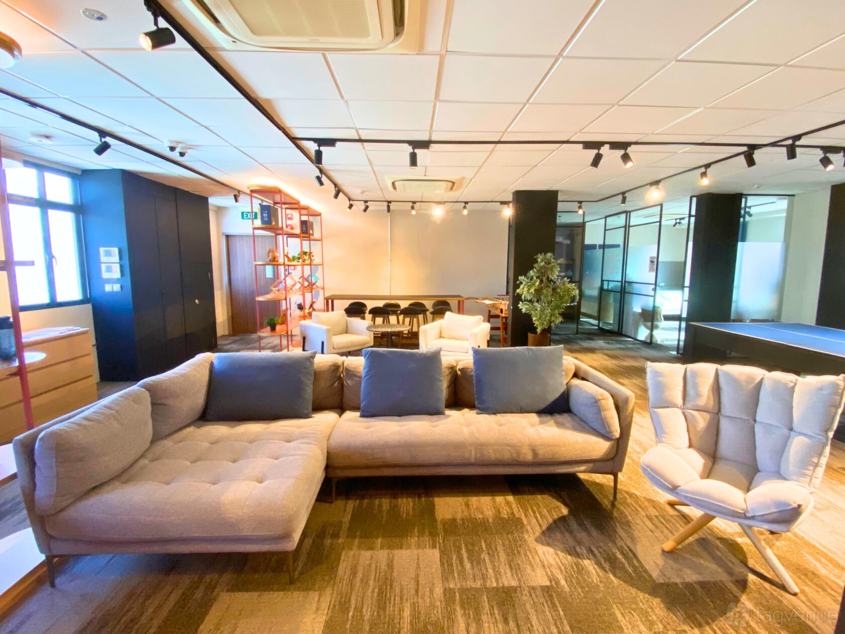 An event space in an office setting with lounge seating, armchairs, and track lighting at Manifest.
