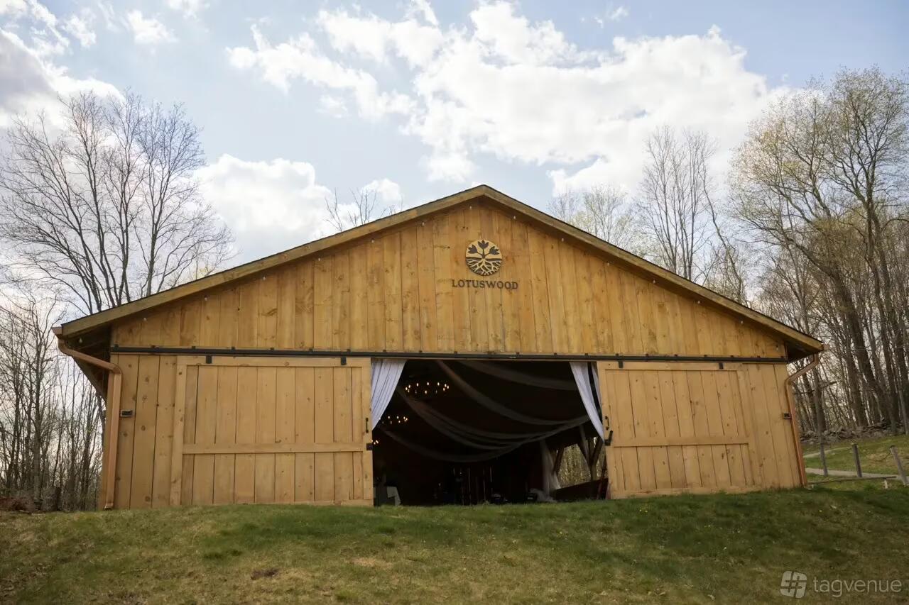 A wooden barn-style event space with open sliding doors and fabric drapes at Lotuswood Organic Wellness Farm.