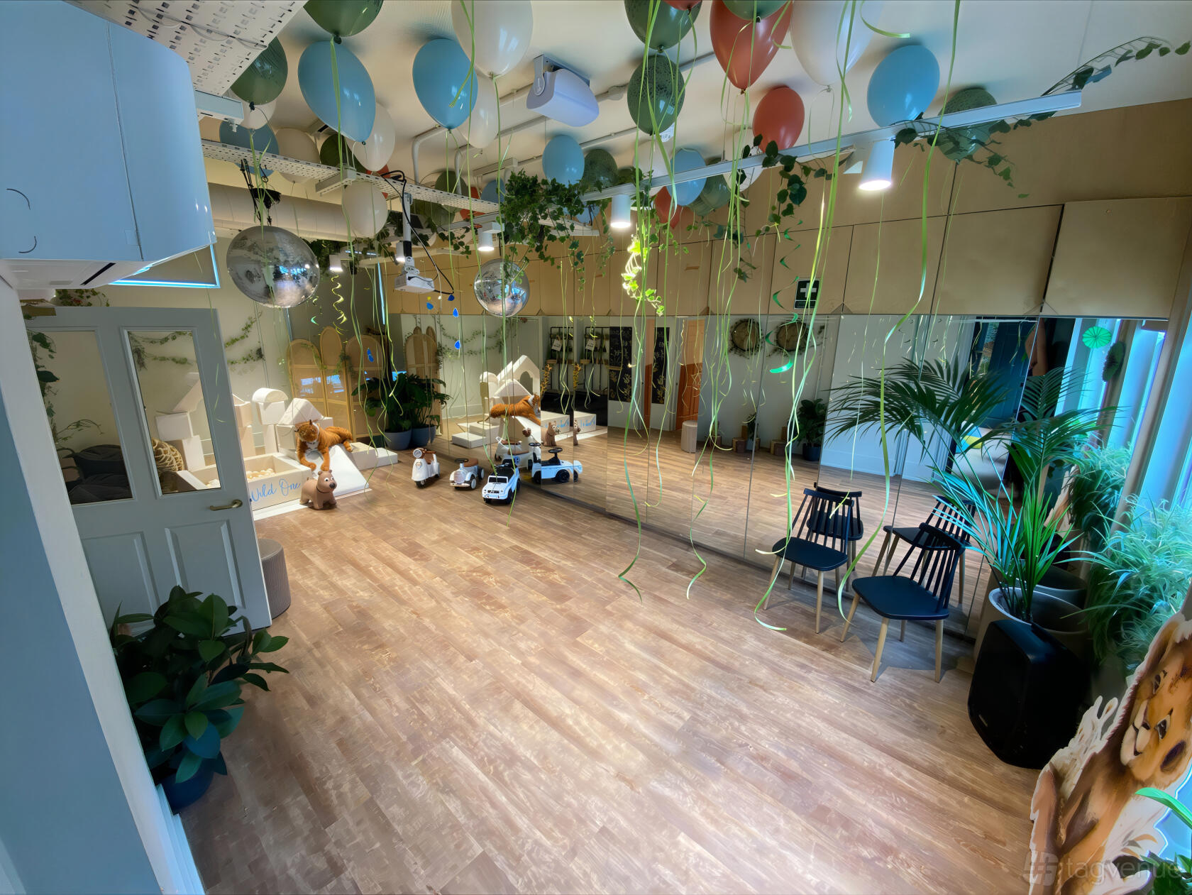 An event venue with mirrored walls, hanging balloons, potted plants, and wooden flooring at b_together.