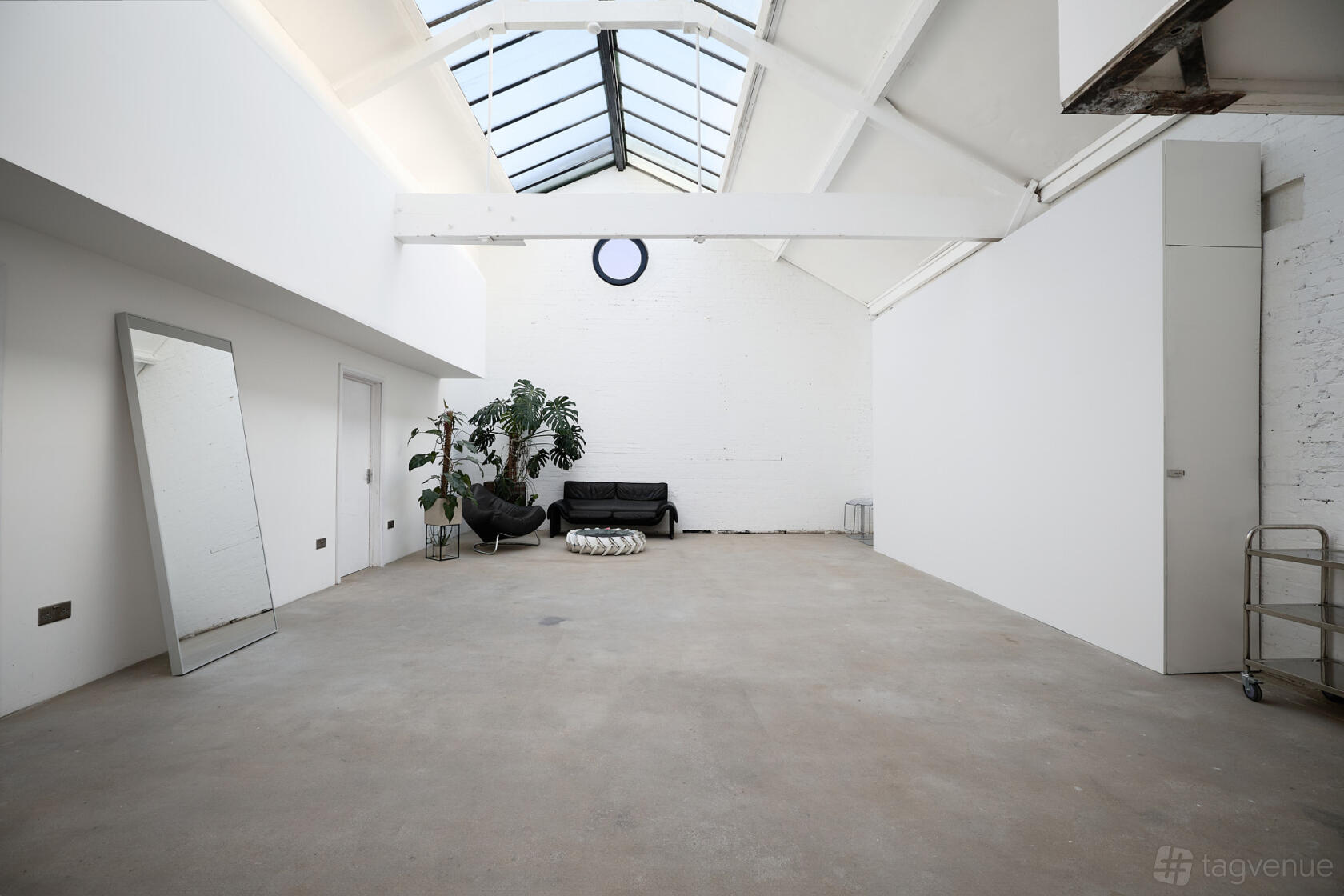 A photo studio with a skylight ceiling, white walls, and minimal furniture at U24.