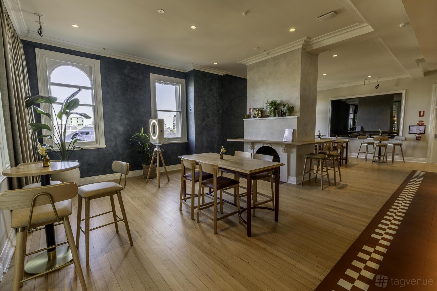 An event space with wooden floors, round tables, large windows, and greenery at Palace Hotel.