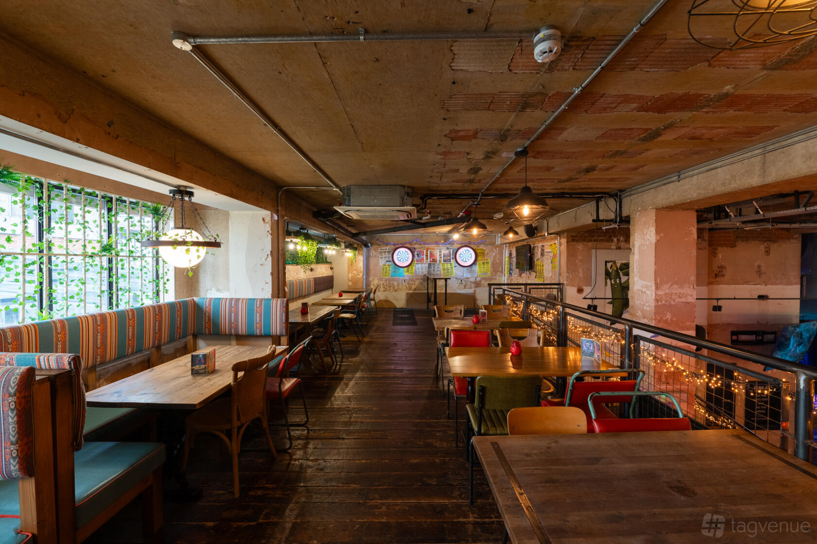 An event space with colorful upholstered booths, wooden floors, and exposed ceiling pipes at Market House.