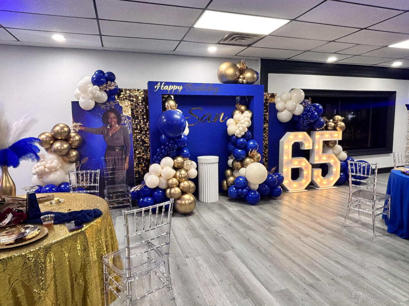 A hall with balloon arrangements, a sequin backdrop, and illuminated marquee numbers at Deexclusive Events.
