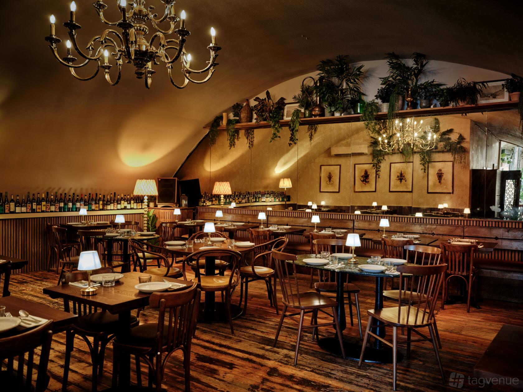 An event space in a restaurant with wooden tables, vintage chandeliers, table lamps, and greenery at Casa do Frango - London Bridge.