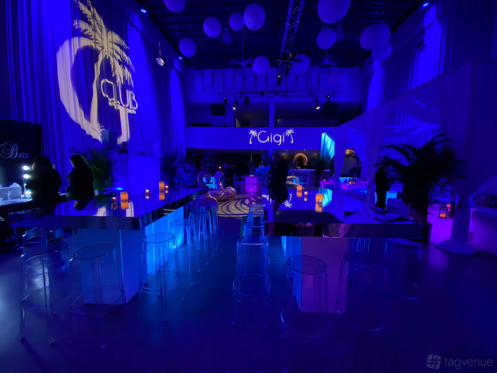 An event venue with blue accent lighting, mirrored tables, clear chairs, and uplighting at KAI studio.