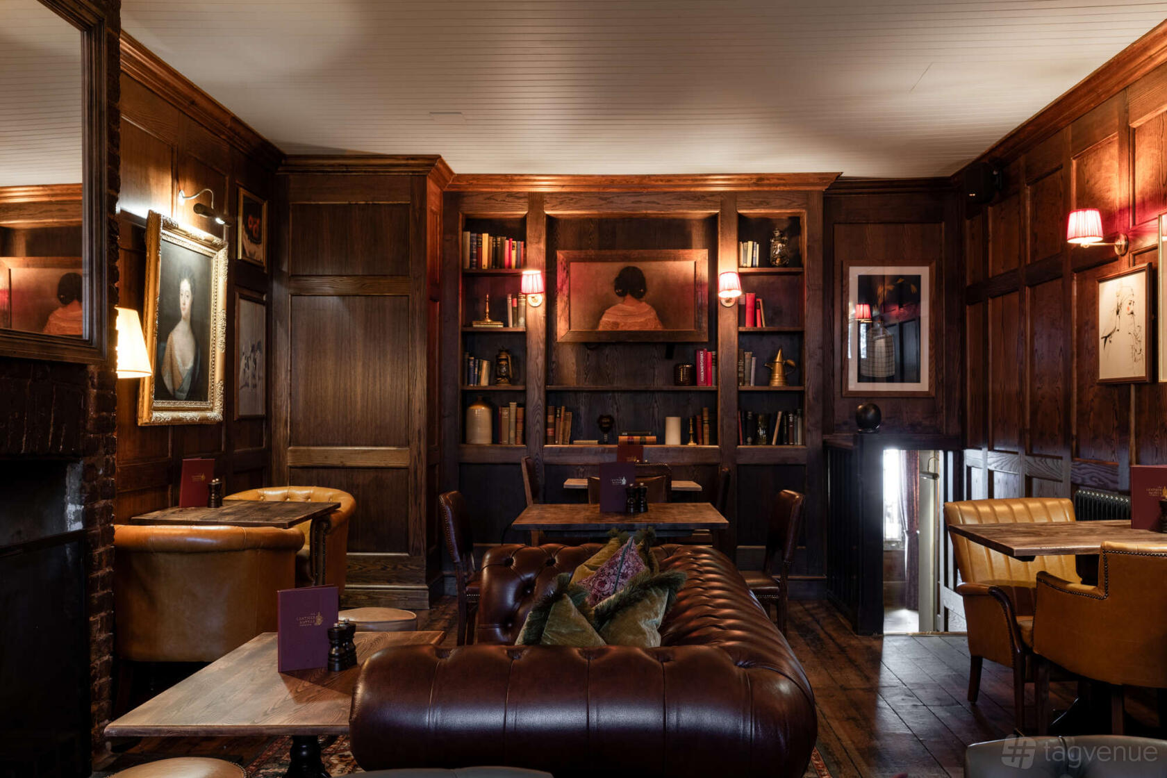 An event space in a pub with wood panelled walls, leather seating, and bookshelves at The Leather Bottle.