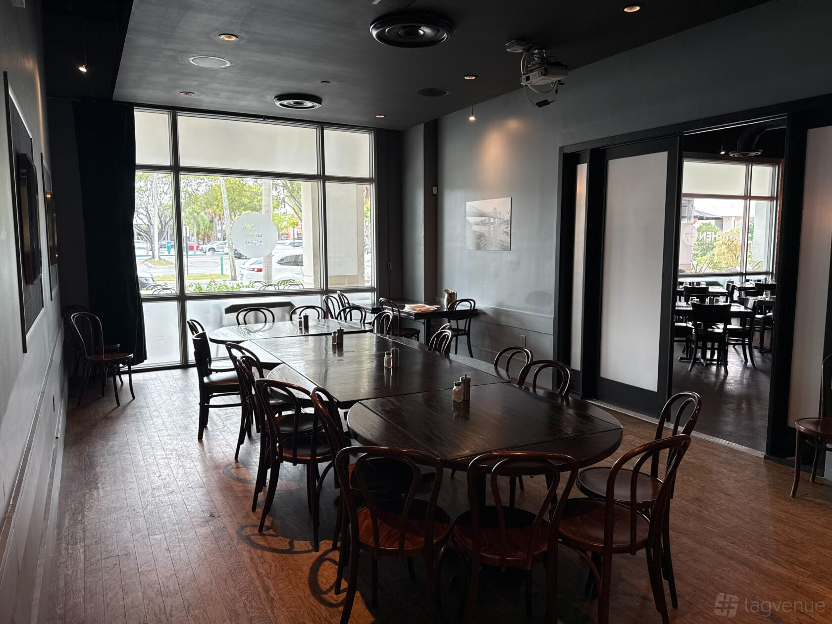 A private function room with dark wood chairs, large windows, and a long rectangular table at Kitchen 57.