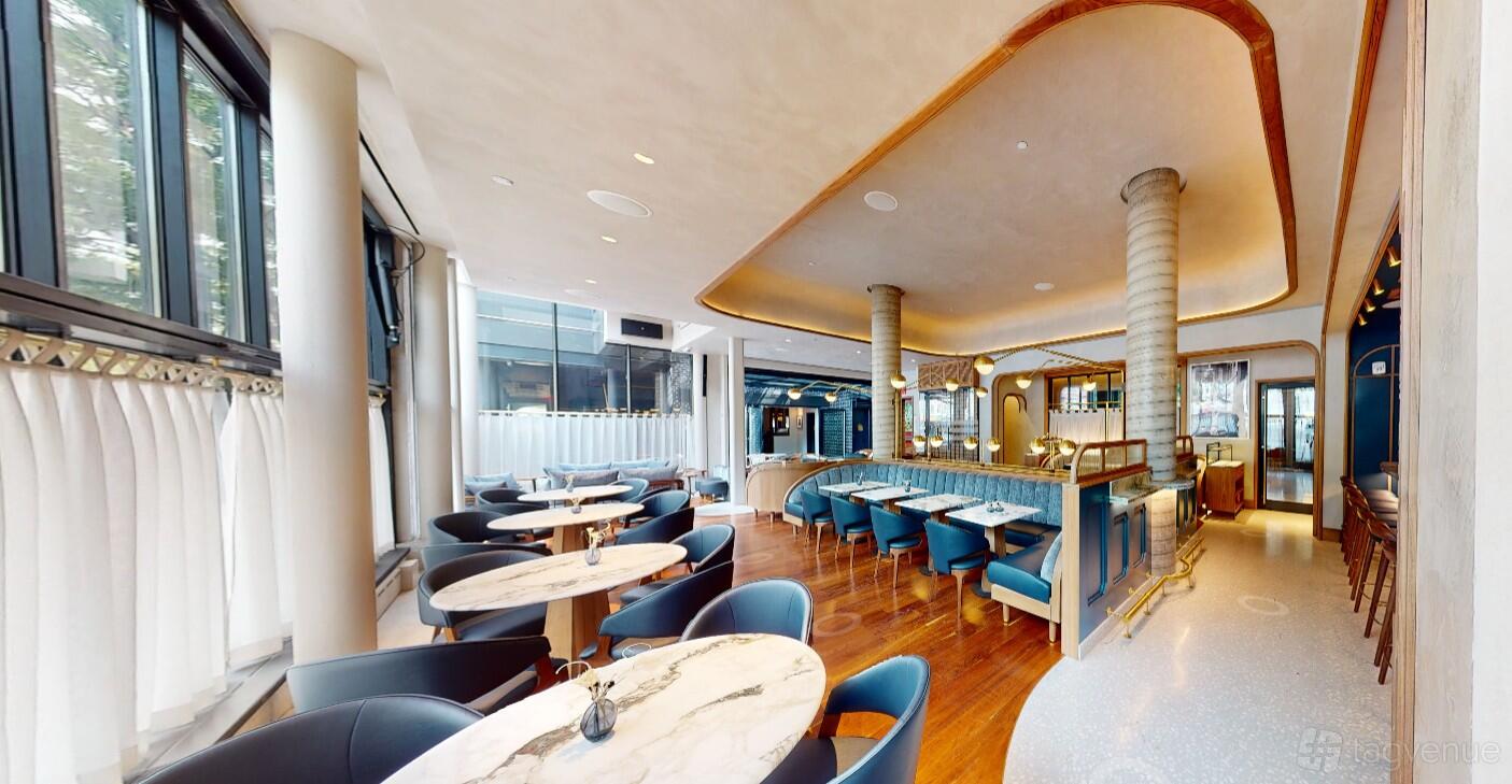 An event venue with marble-topped round tables, blue upholstered chairs, and floor-to-ceiling windows at The Merchant Hotel.