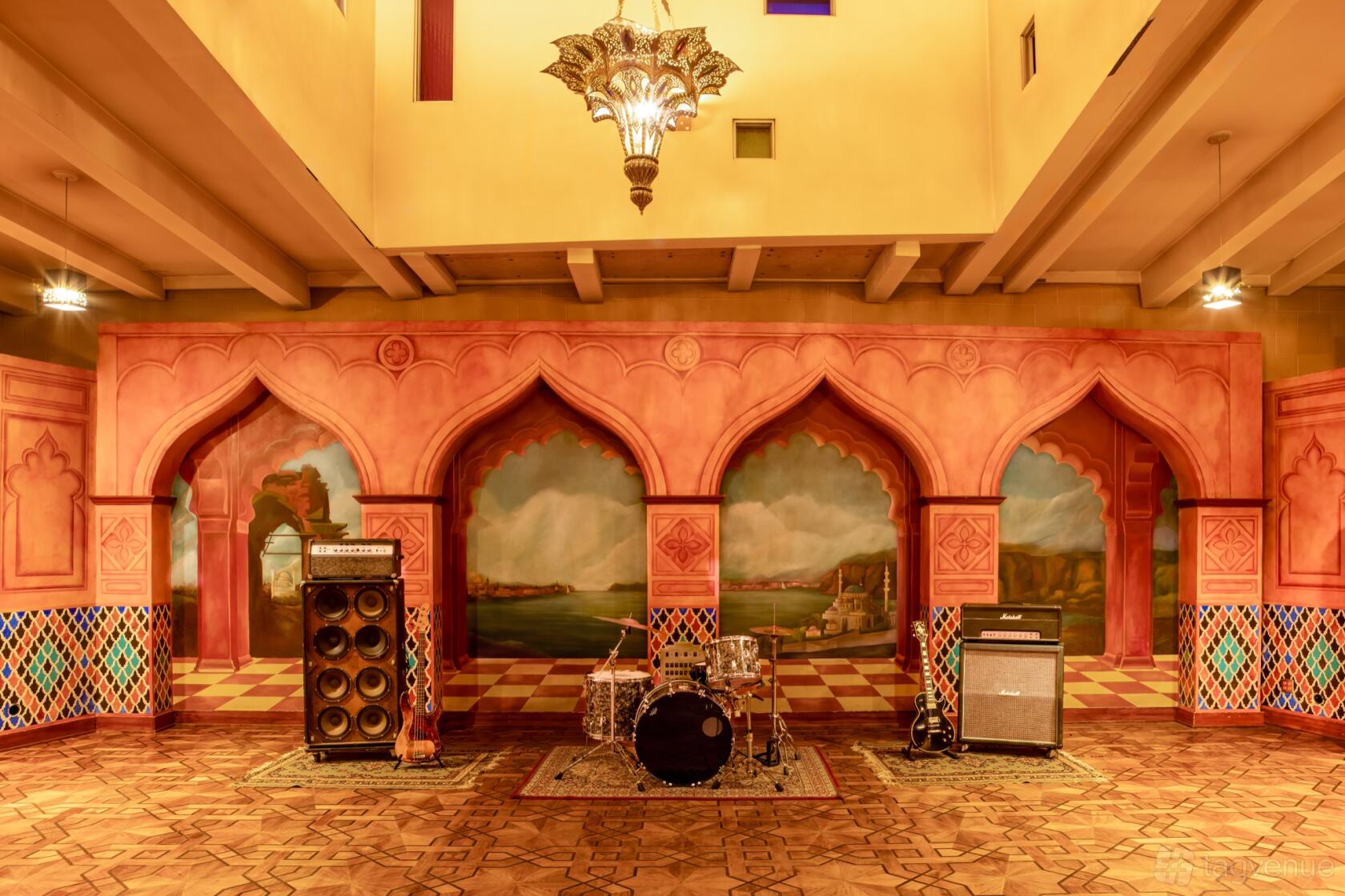 A recording studio with decorative arches, painted murals, and a drum kit with amplifiers at NRG Recording Studios.