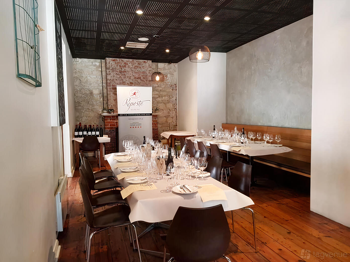 A restaurant dining room with exposed brick walls, wood floors, and banquet seating at Jimmies Restaurant.