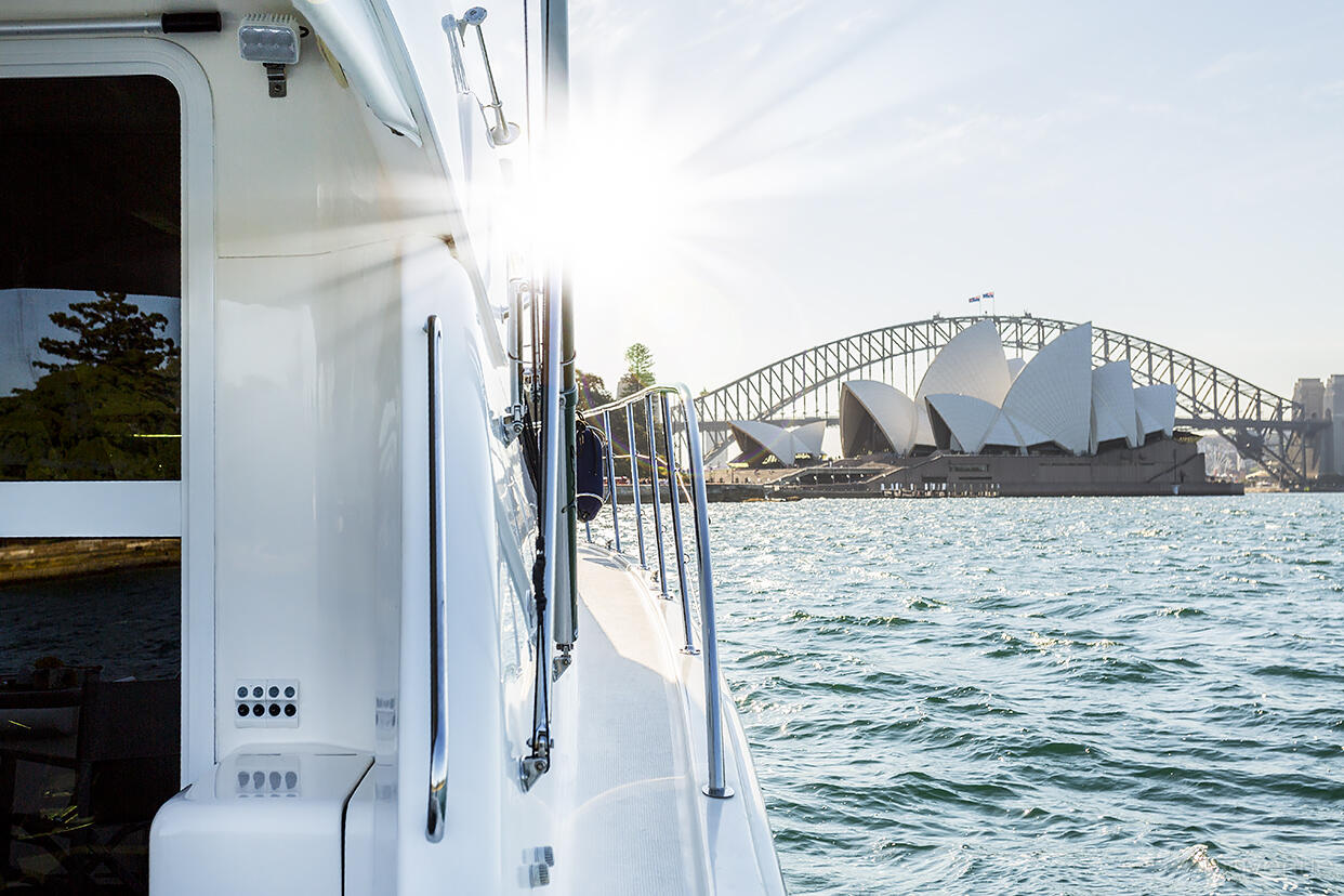 A charter boat with stainless steel railings on the water near the Sydney Opera House at MV Ocean Blue.