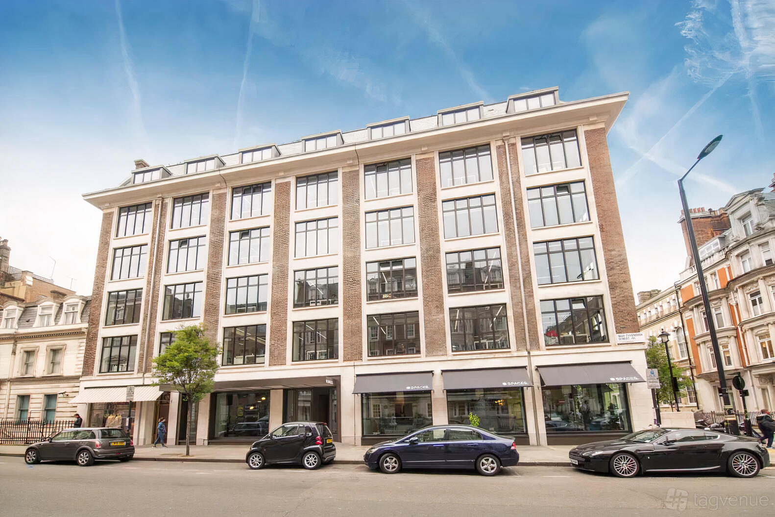 A meeting centre with a red brick and white-framed window façade facing a city street at Spaces - London, Spaces Fitzrovia.
