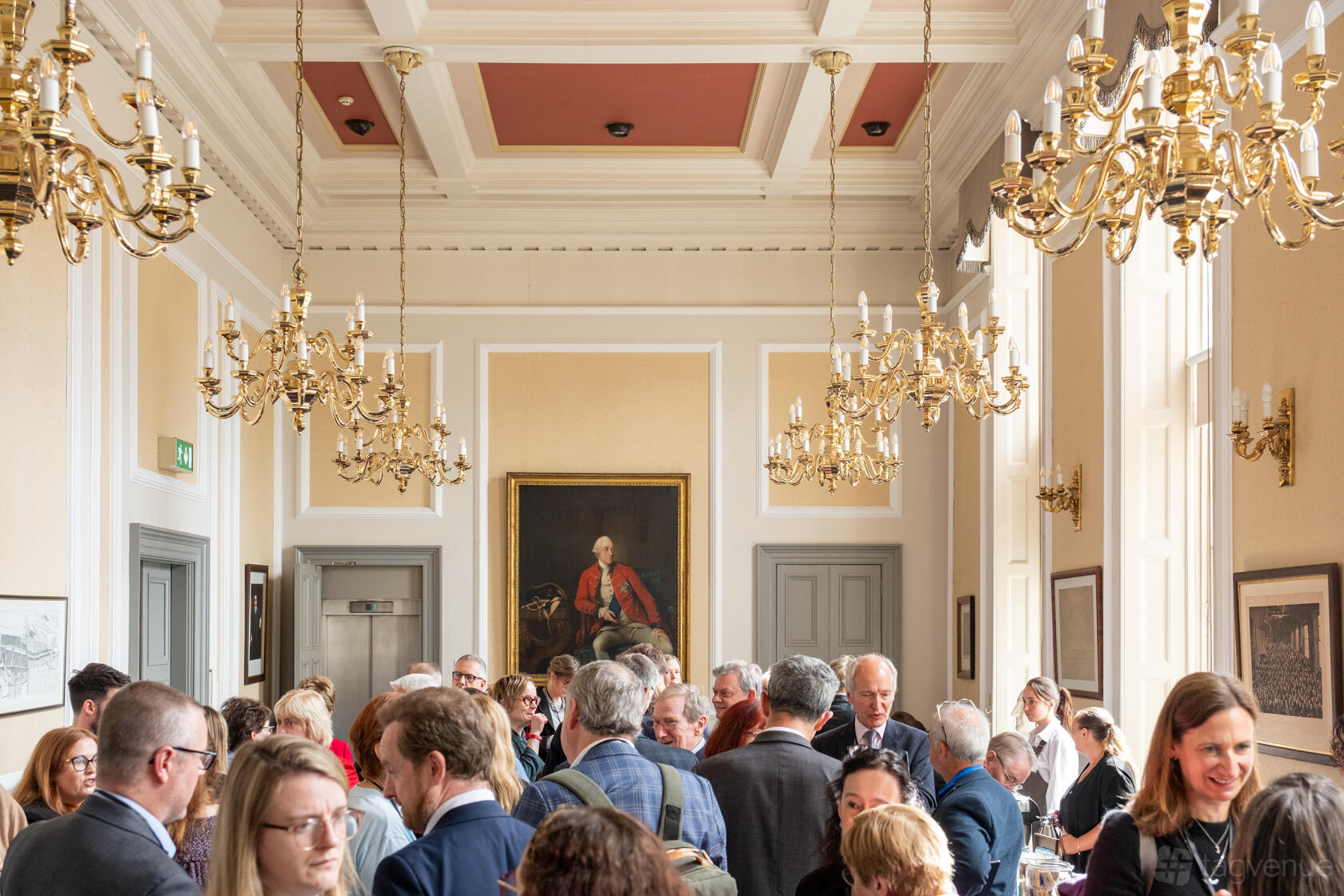 An academic event space with tall windows, chandeliers, and classical paintings at The Royal Society of Edinburgh.