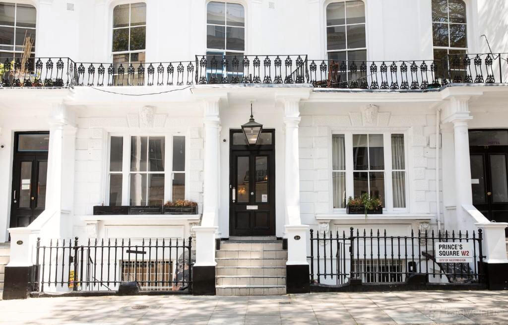 A hotel entrance with black railings, white columns, and a central black door at Princes Square Hotel.