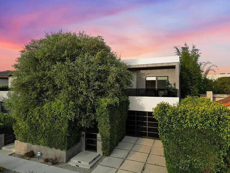 A two-story house with large windows, dark accents, and lush greenery at The Harper Six.