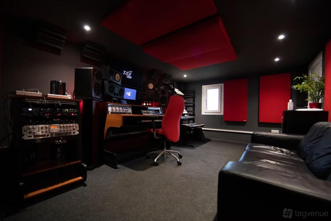 A recording studio with acoustic panels, mixing desk, large monitors, and a sofa at Red room studios.