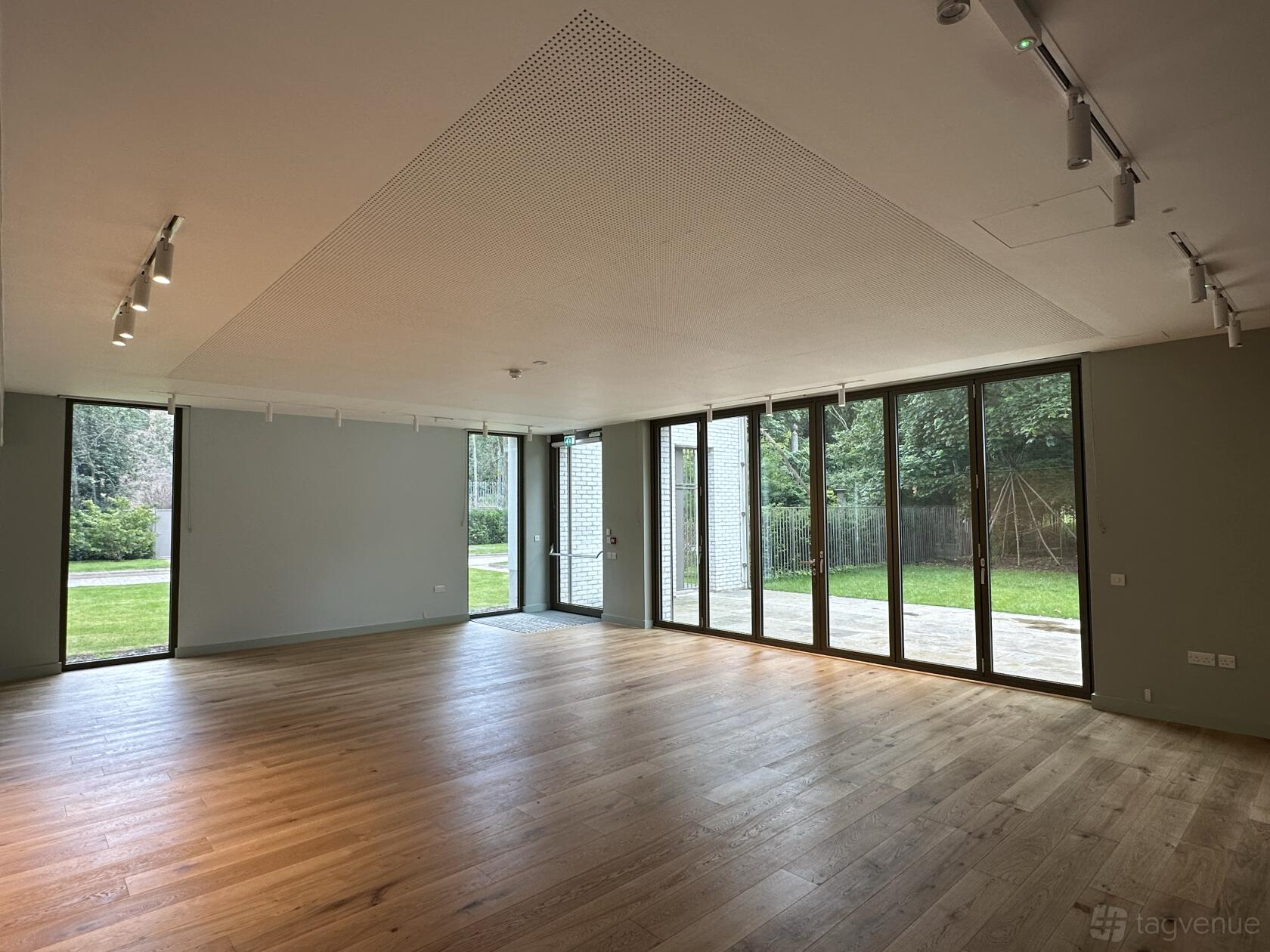 An event space in a cafe with floor-to-ceiling windows, wood flooring, and garden views at Abney Park cafe.