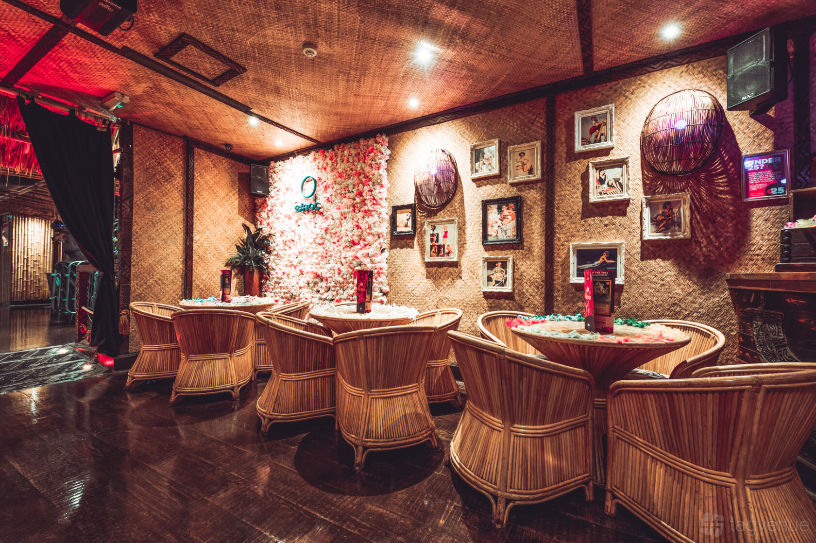 A nightclub lounge with bamboo chairs, woven walls, floral garland decor, and framed artwork at Lola Lo Reading.