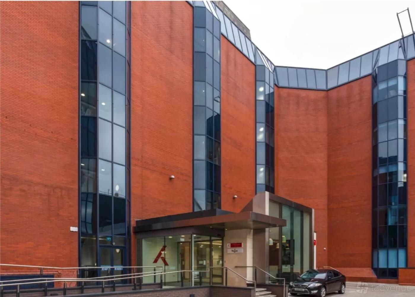 A meeting centre with a red brick exterior, large glass windows, and a covered entrance at Regus - Birmingham, Apex House.