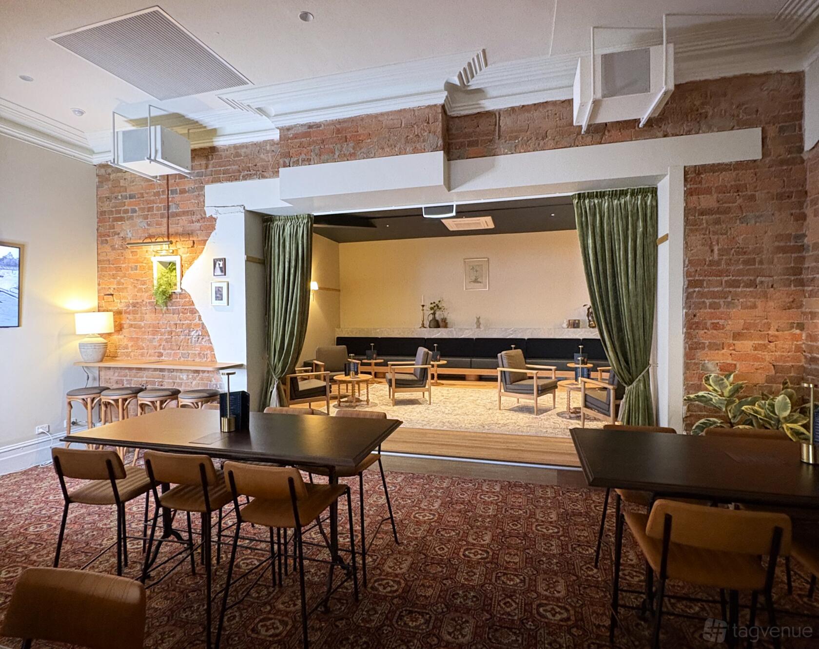 A hotel pub lounge with exposed brick walls, green curtains, and stage seating at Palace Hotel.