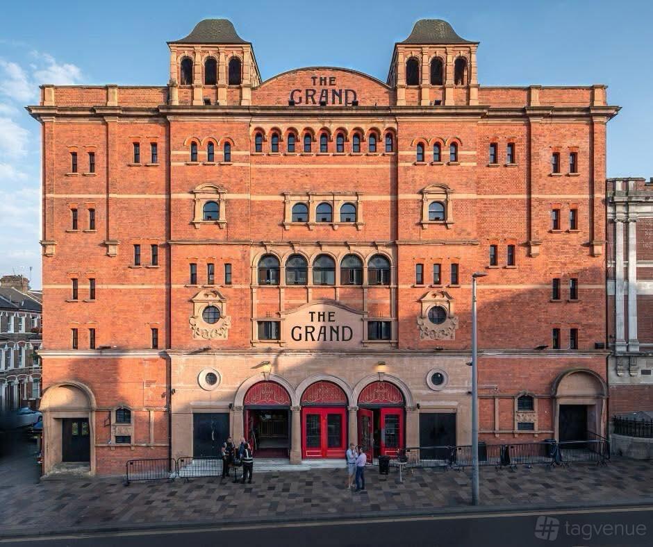 A versatile event space with a historic red brick facade, arched windows, and large entrance doors at The Clapham Grand.