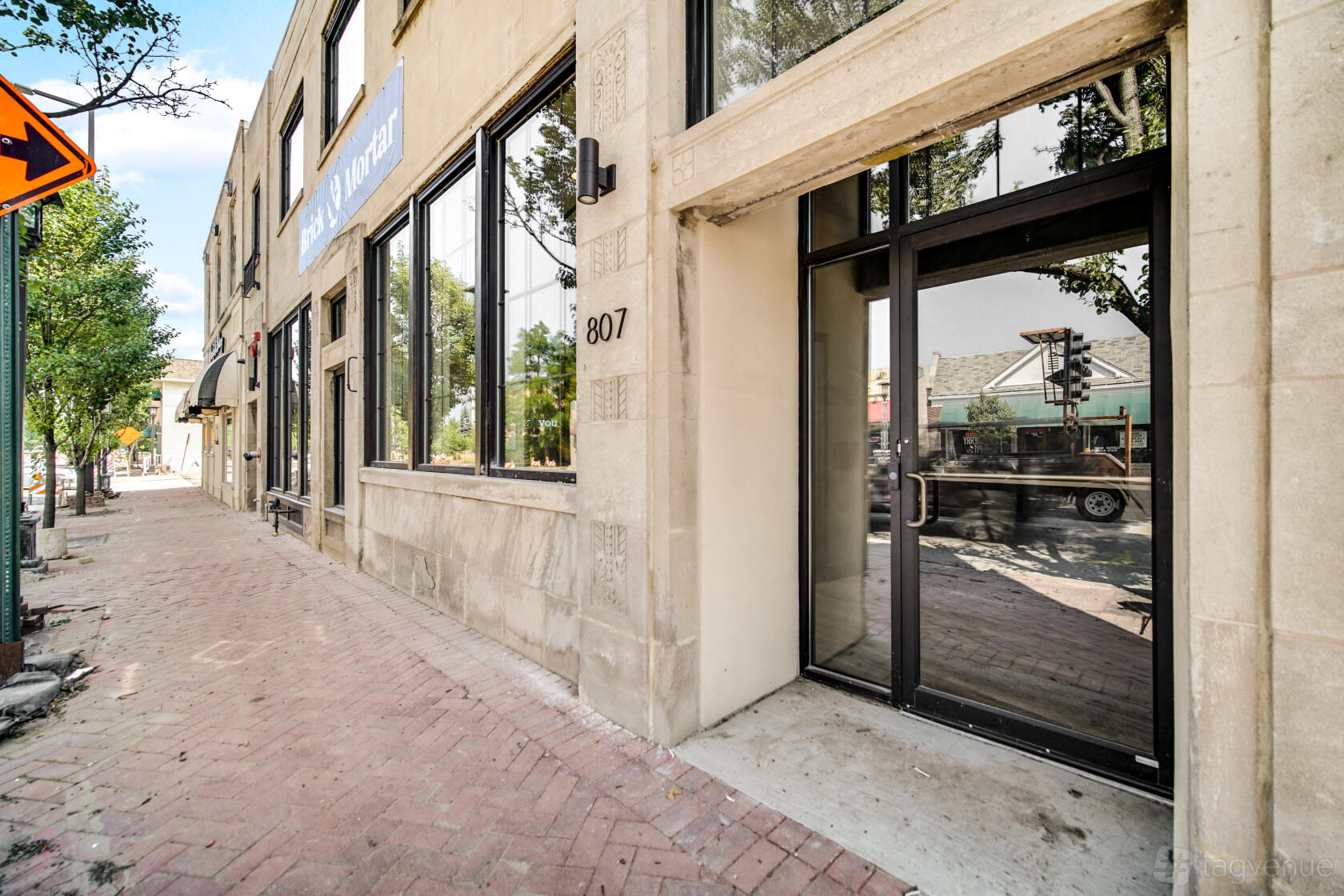 A coworking space with large street-facing windows, stone façade, and glass entry door at Brick & Mortar Deerfield.