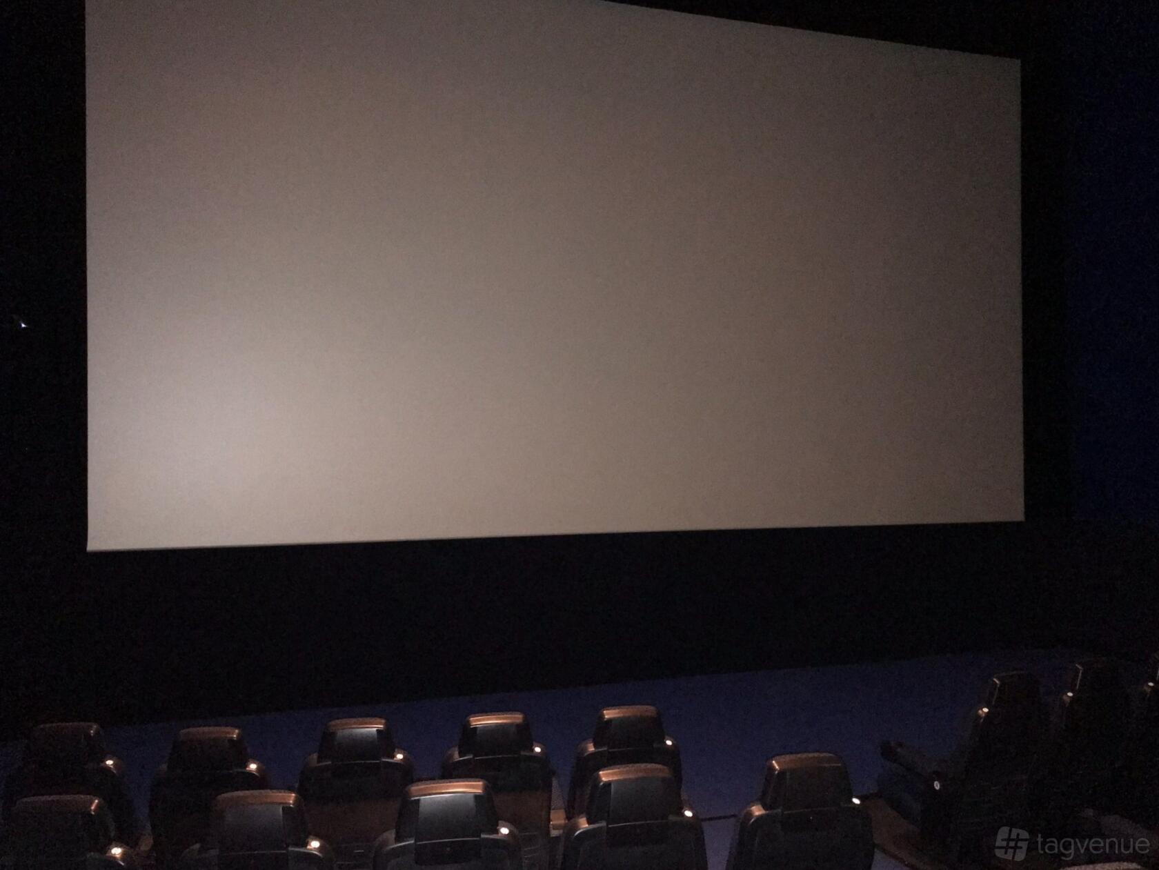 A cinema auditorium with rows of black seats facing a large blank screen at Vue Birmingham - Star City.